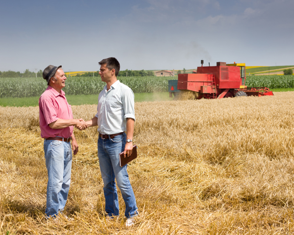 Farmer and businessman shaking hands on wheat field