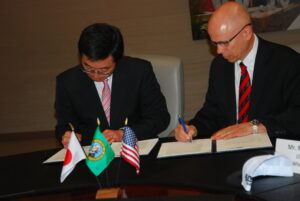 Two men seated at a table signing documents