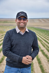 Photo of Surendra Singh standing in a spring wheat field. 