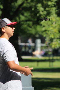 A man holds a drone controller and watches the flight of a small drone