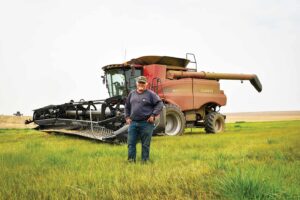 Third-generation wheat farmer, Mike Carstensen standing in front of his red combine on his dryland farm near Almira, Washington.