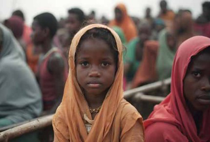 A Sudanese refugee girl in a boat with a crowd of people. 